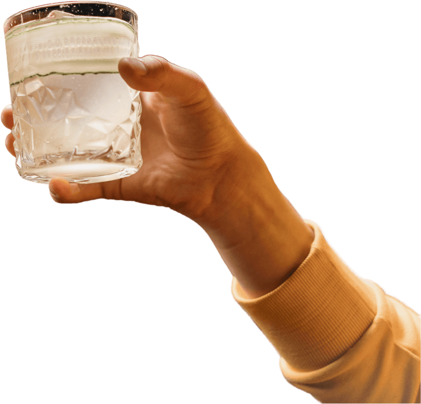 A hand holding a glass of water, with a blurred background.